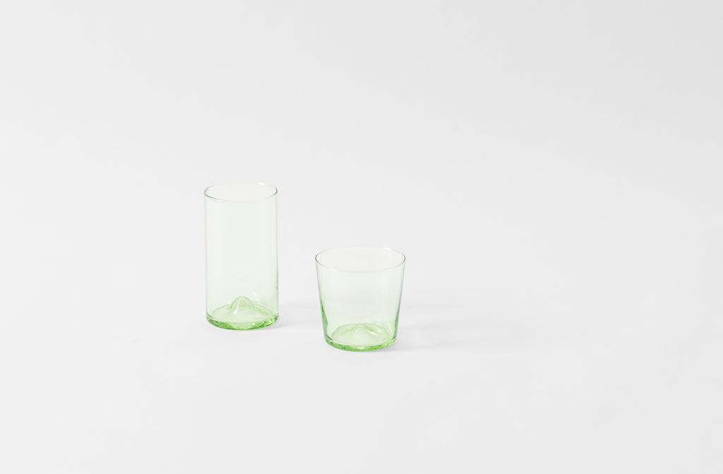 Two green glass tumblers on a white background. Default