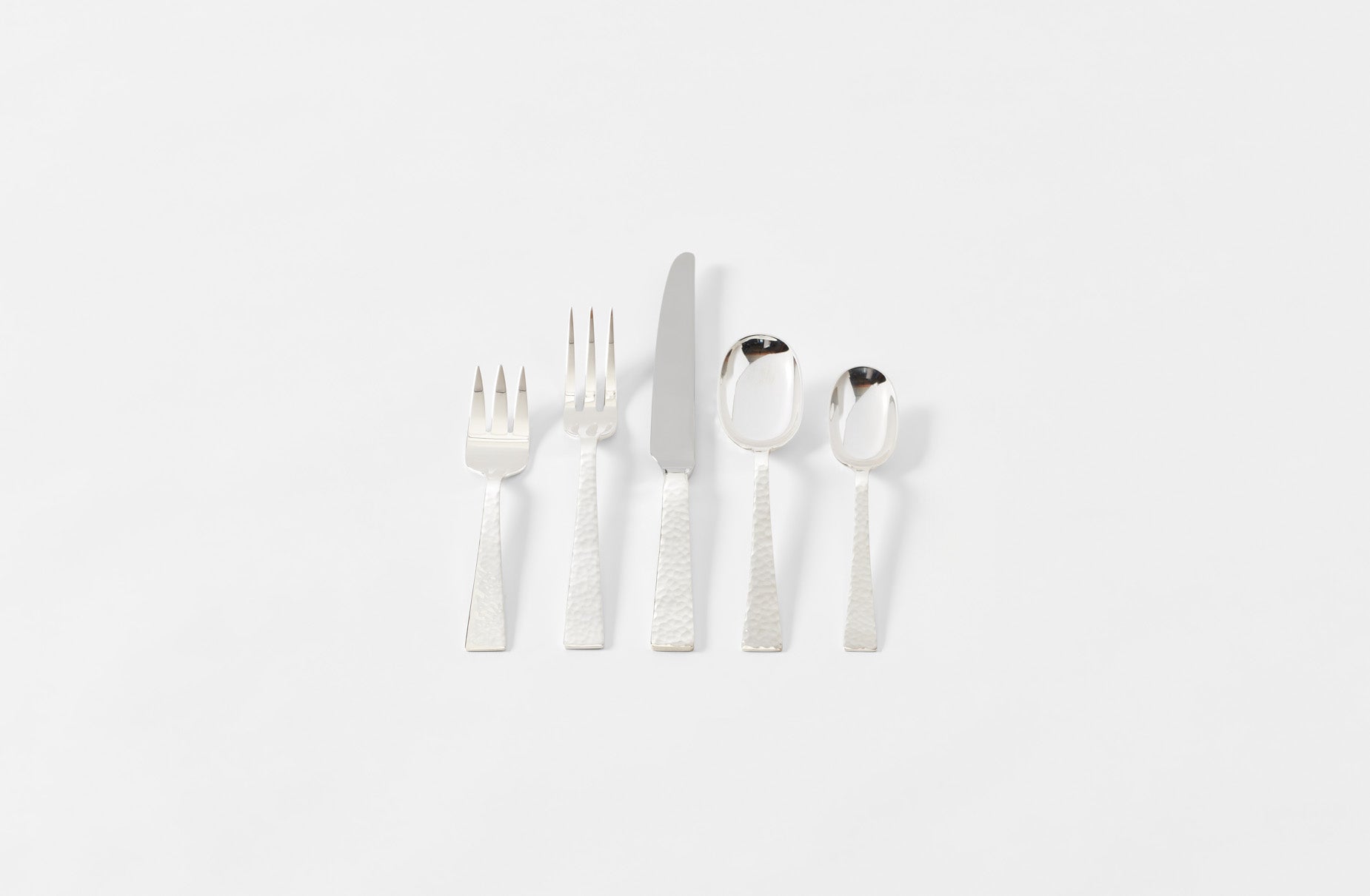 Set of silver cutlery including forks, knives, and spoons on a white background
