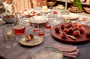 Garden table set with stripe tablecloth and glass hurricanes carafe and oaxacan glasses filled with rose