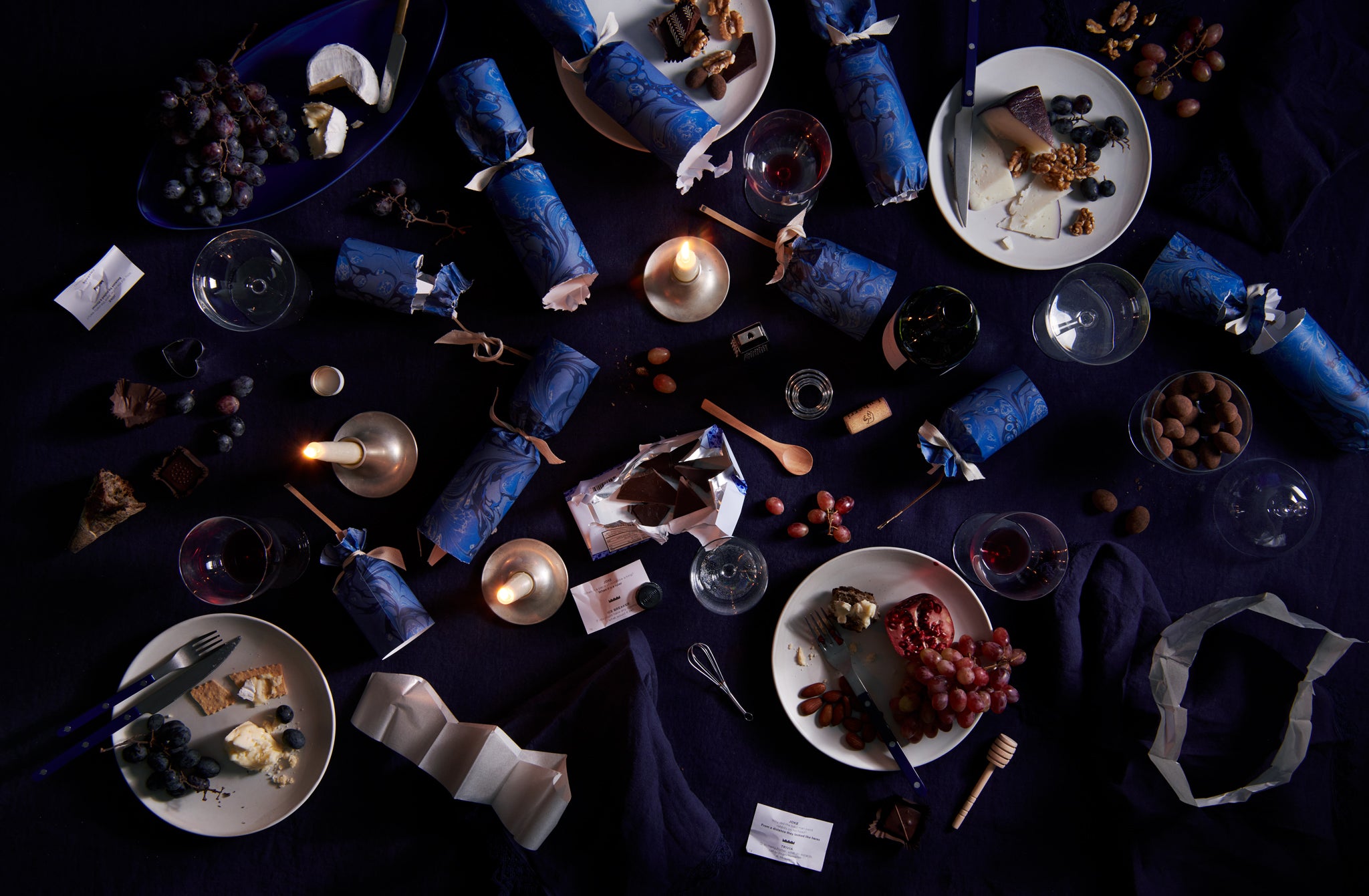 After celebration dinner table with MARCH cracker remnants and Ted Muehling candle holders with vintage lapis bistrot flatware mingling on a tabletop