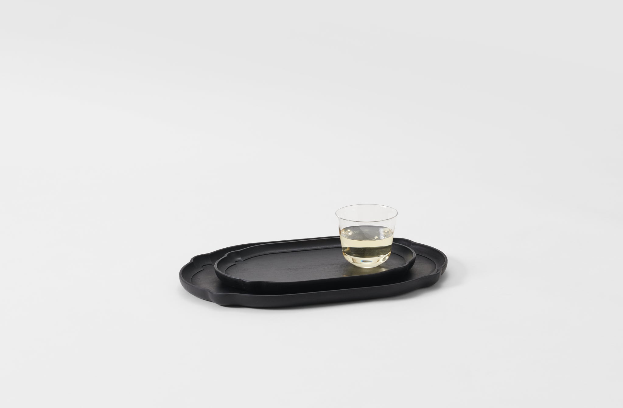 Black tray with a glass of wine on a light gray background. Default