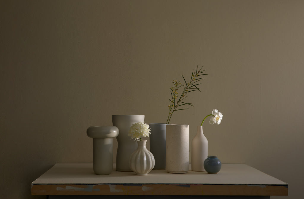 Assortment of vases in cream and grey on tabletop.