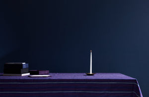 tensira plum and navy stripe tablecloth set with michael verheyden letter boxes stationary and single ilse crawford brass candlestick and lit taper candle