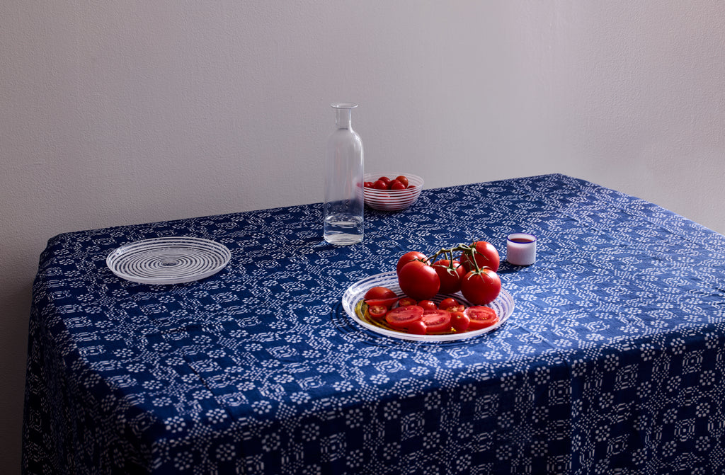 Summery table set with Italian Murano glass dinnerware on hand-printed checkered floral indigo tablecloth with.