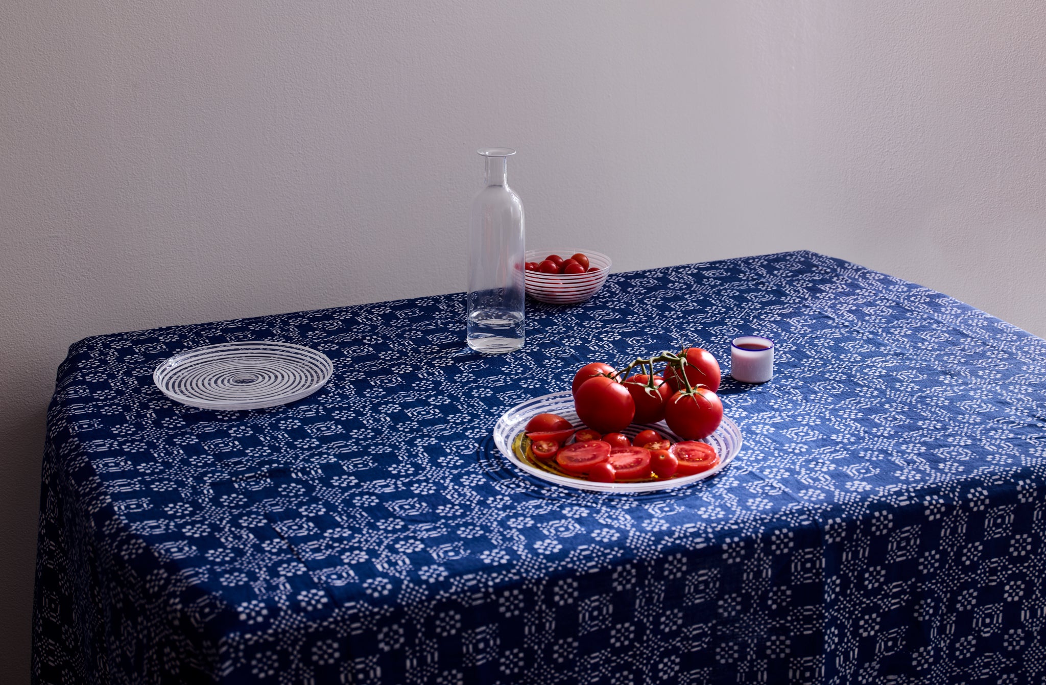 Summery table set with Italian Murano glass dinnerware on hand-printed checkered floral indigo tablecloth with.