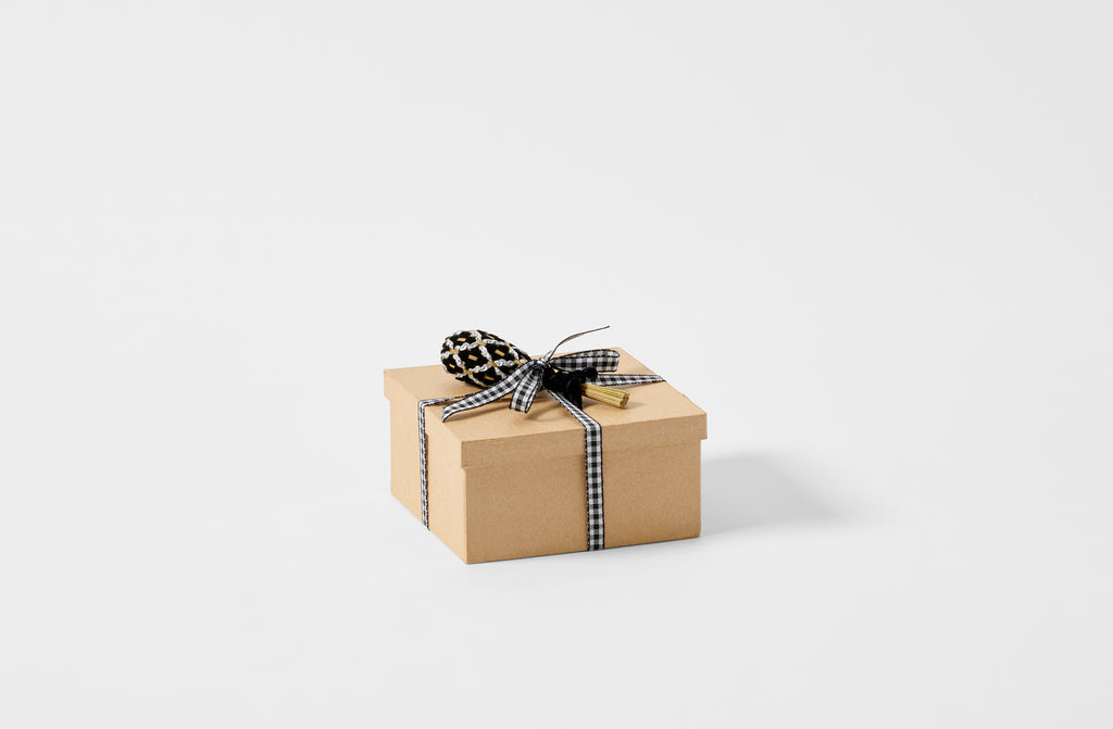 Black and silver faberge petite lavender wand shown as gift on top of a kraft box