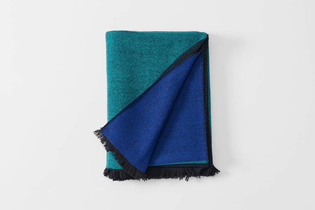 Folded blue scale cashmere throw blanket with detail of reverse.
