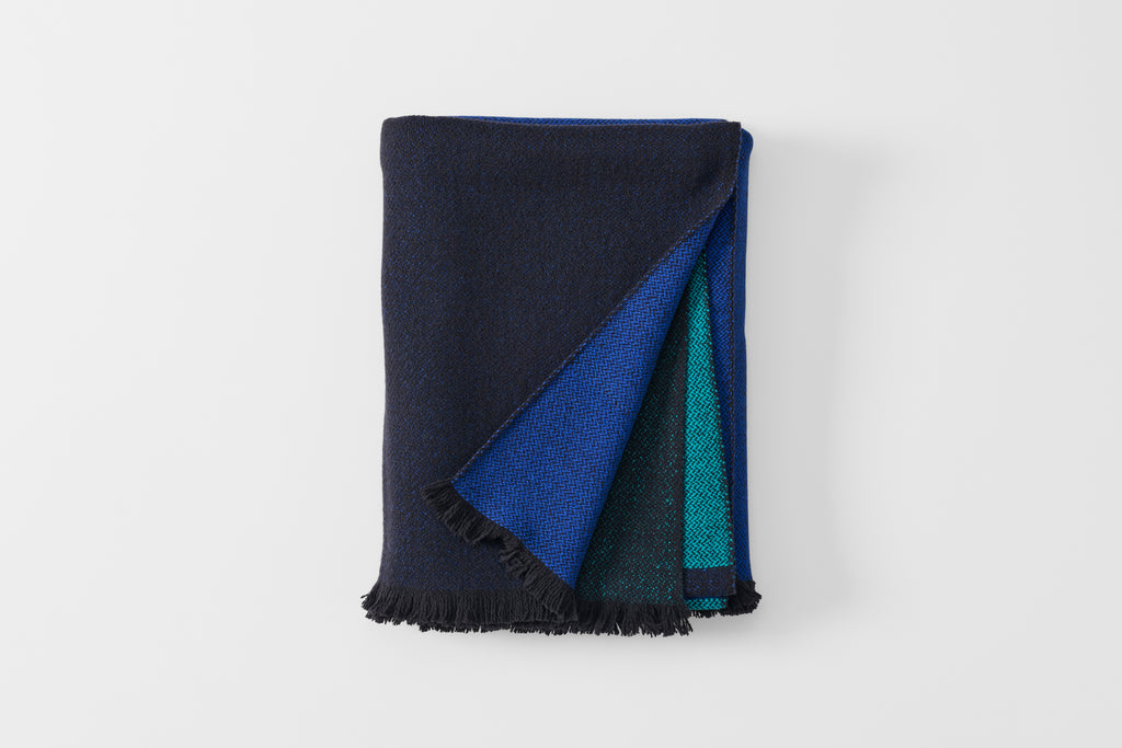Folded blue scale cashmere throw blanket with detail of reverse.