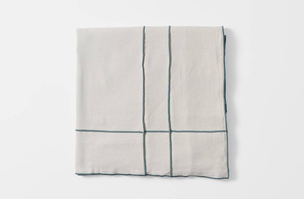 Folded embroidered grid tisana tablecloth.