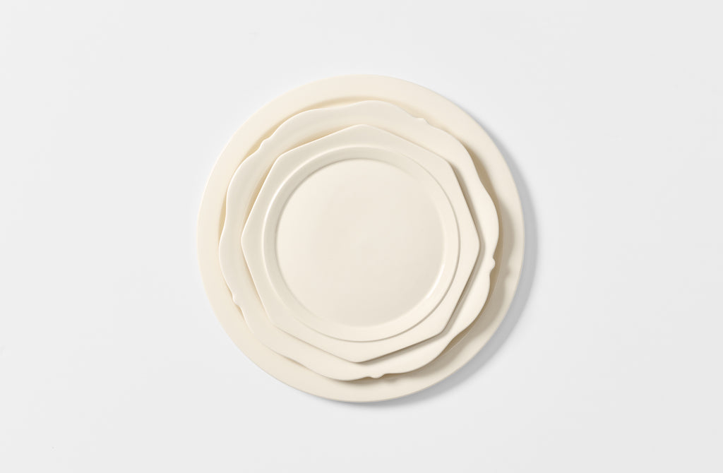 Set of white ceramic plates of different sizes on a light gray background. Default