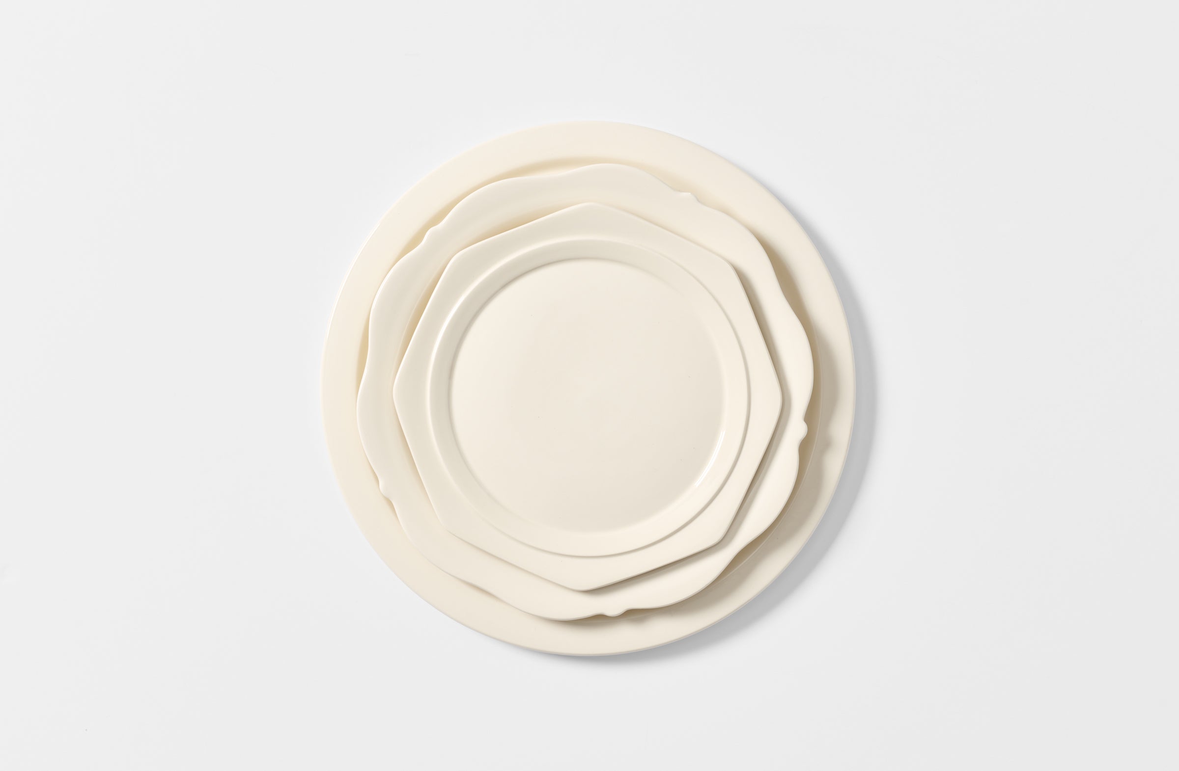 Set of white ceramic plates of different sizes on a light gray background. Default