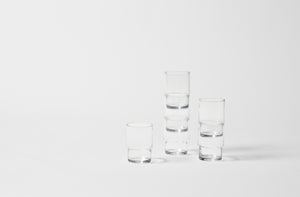 Six glass stacking tumblers on white background.