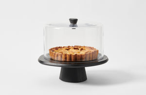 Kelly Wearstler black ash cake stand with knobbed glass dome holding rustic pie