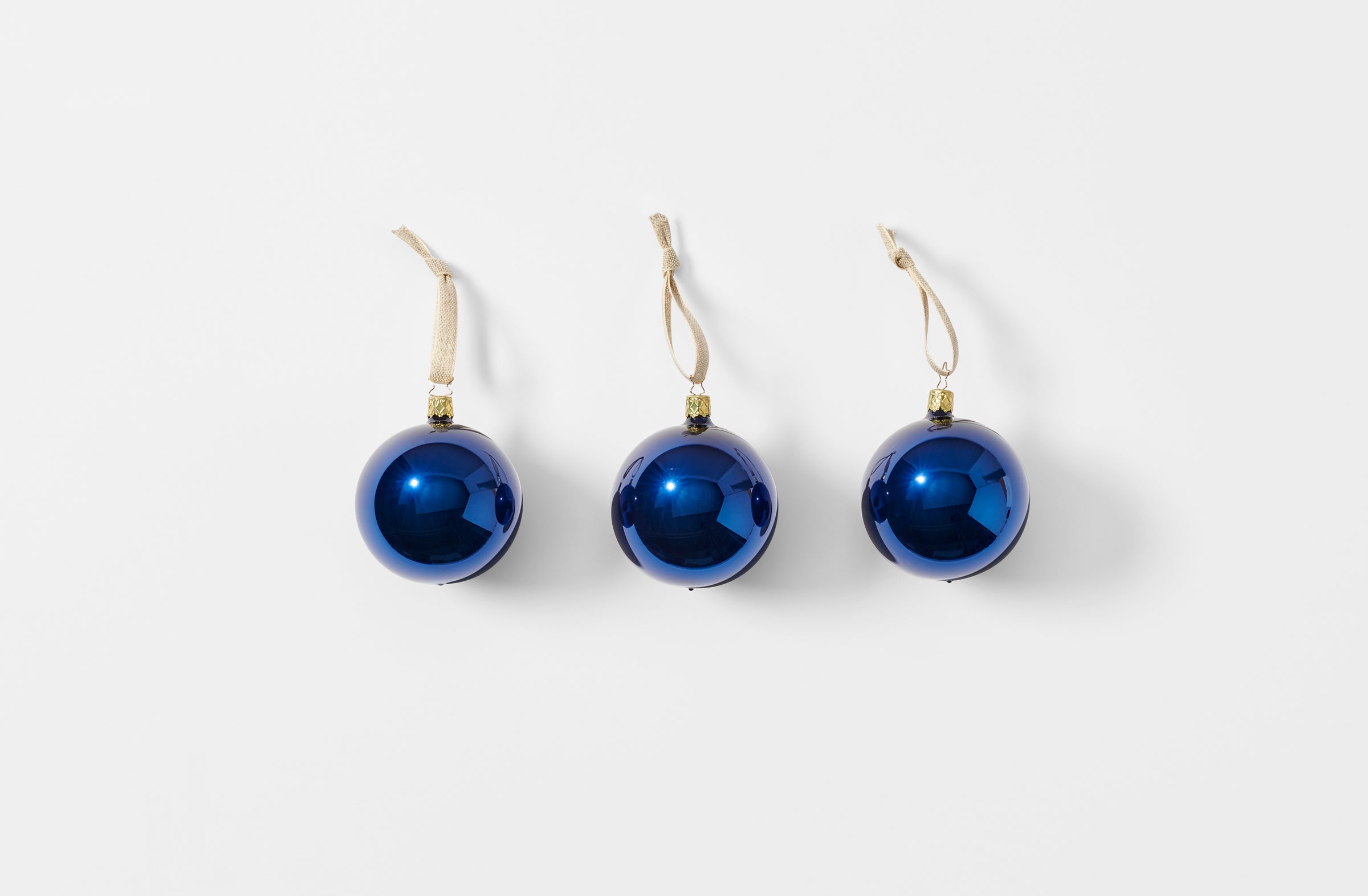 Three midnight glass ball ornaments strung with linen tape