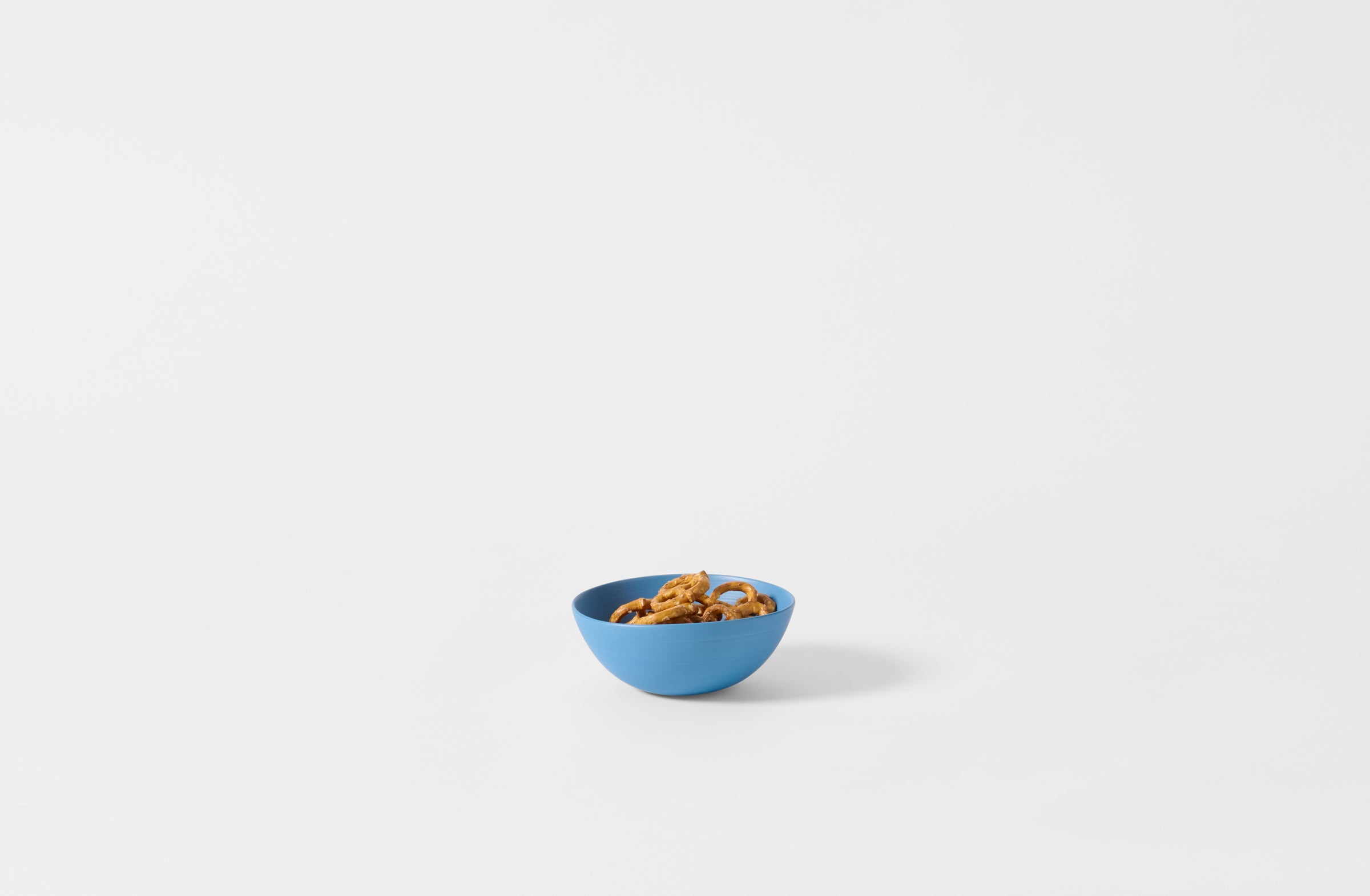 Extra small Rina Manardi turquoise shallow bowl holding pretzels.