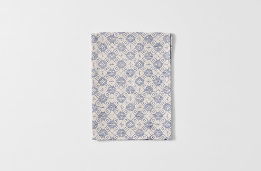 Folded Tori Murphy indigo tapestry kitchen towel.