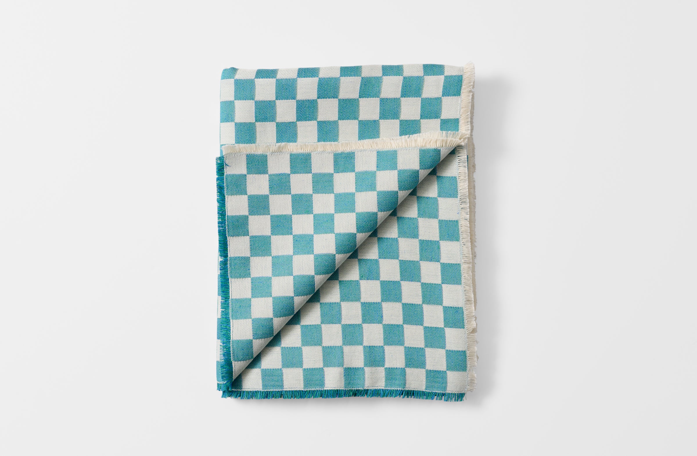 Folded turquoise check tablecloth with detail of reverse.