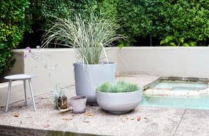 Poolside-vignette-of-aluminum-planters-planted-with-grass-and-faye-toogood-aluminum-milking-stool
