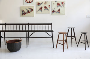 At-MARCH-Sawkille-rabbit-bench-in-ebonized-with-walnut-stools-and-carriemae-smith-meat-paintings-hung-behind