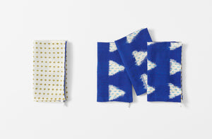 four folded gregory parkinson indigo sky napkins with one napkin folded to the reverse pattern of khaki diamonds on cream
