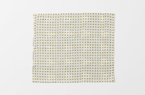 one unfolded greogory parkinson indigo sky napkin showing the reverse pattern of small khaki diamonds on cream