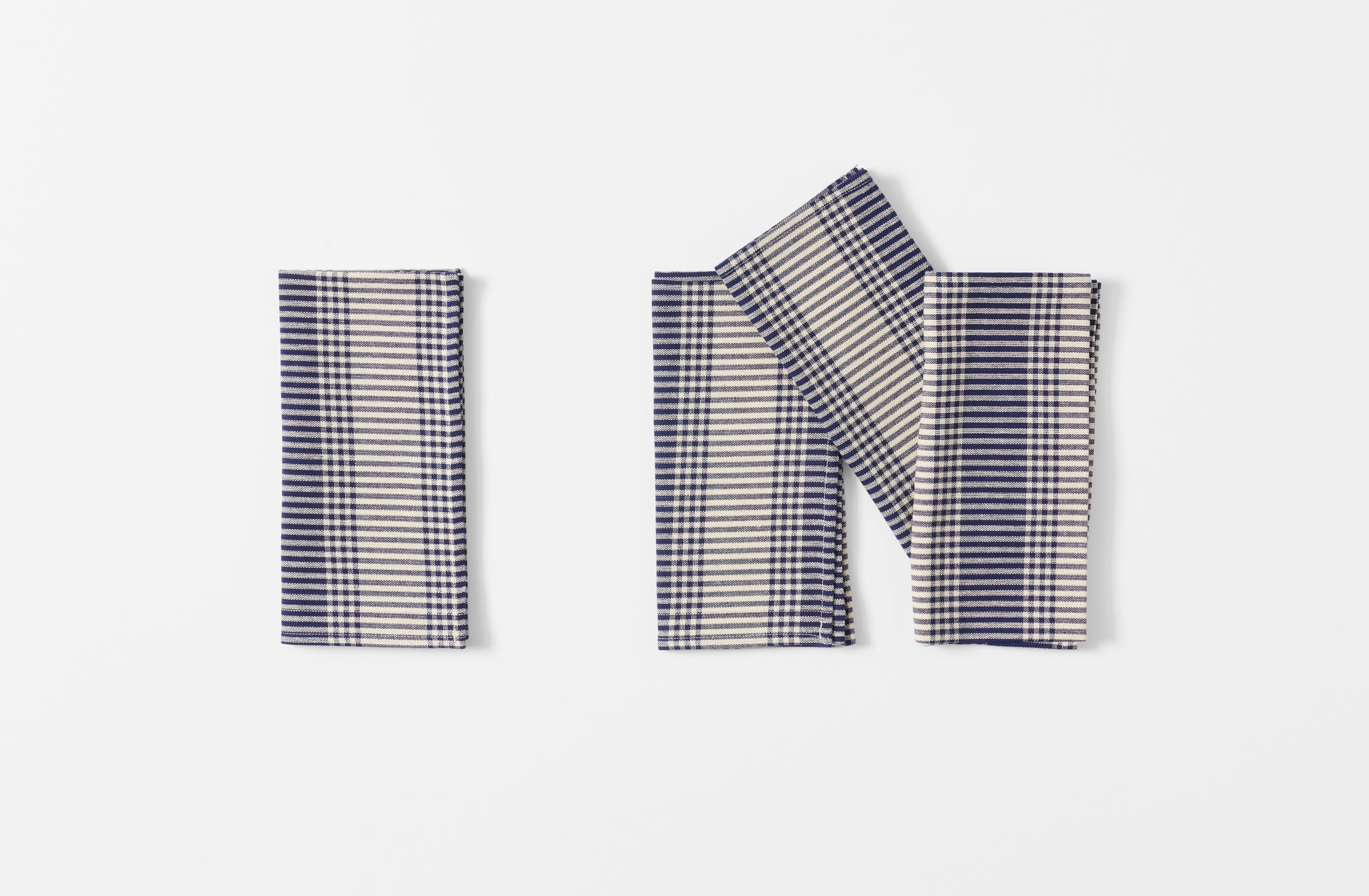 four tensira navy and natural tartan plaid napkins shown folded