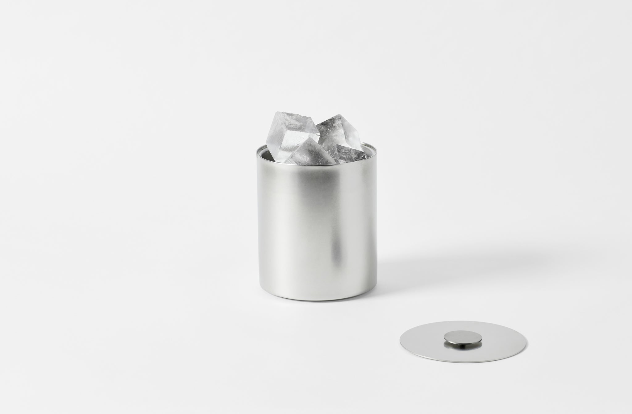 stile pewter steel ice bucket with a matte finish with the lid off and to one side and set with large ice cubes