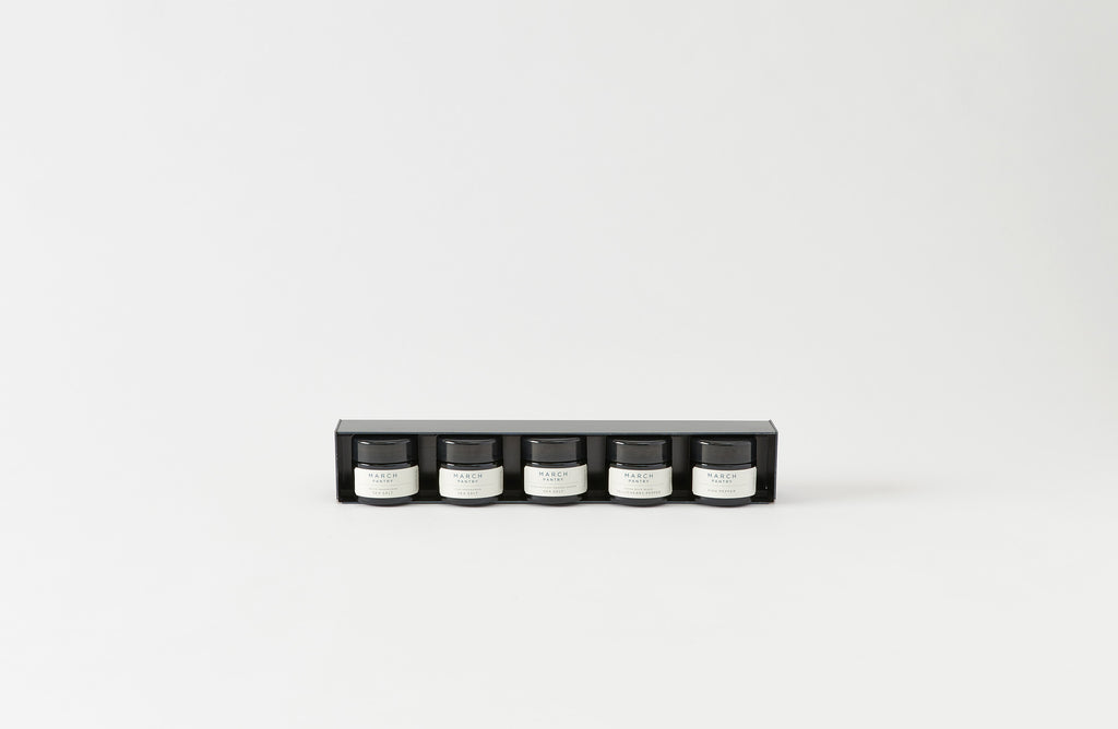 Set of four small containers in a black holder on a white background