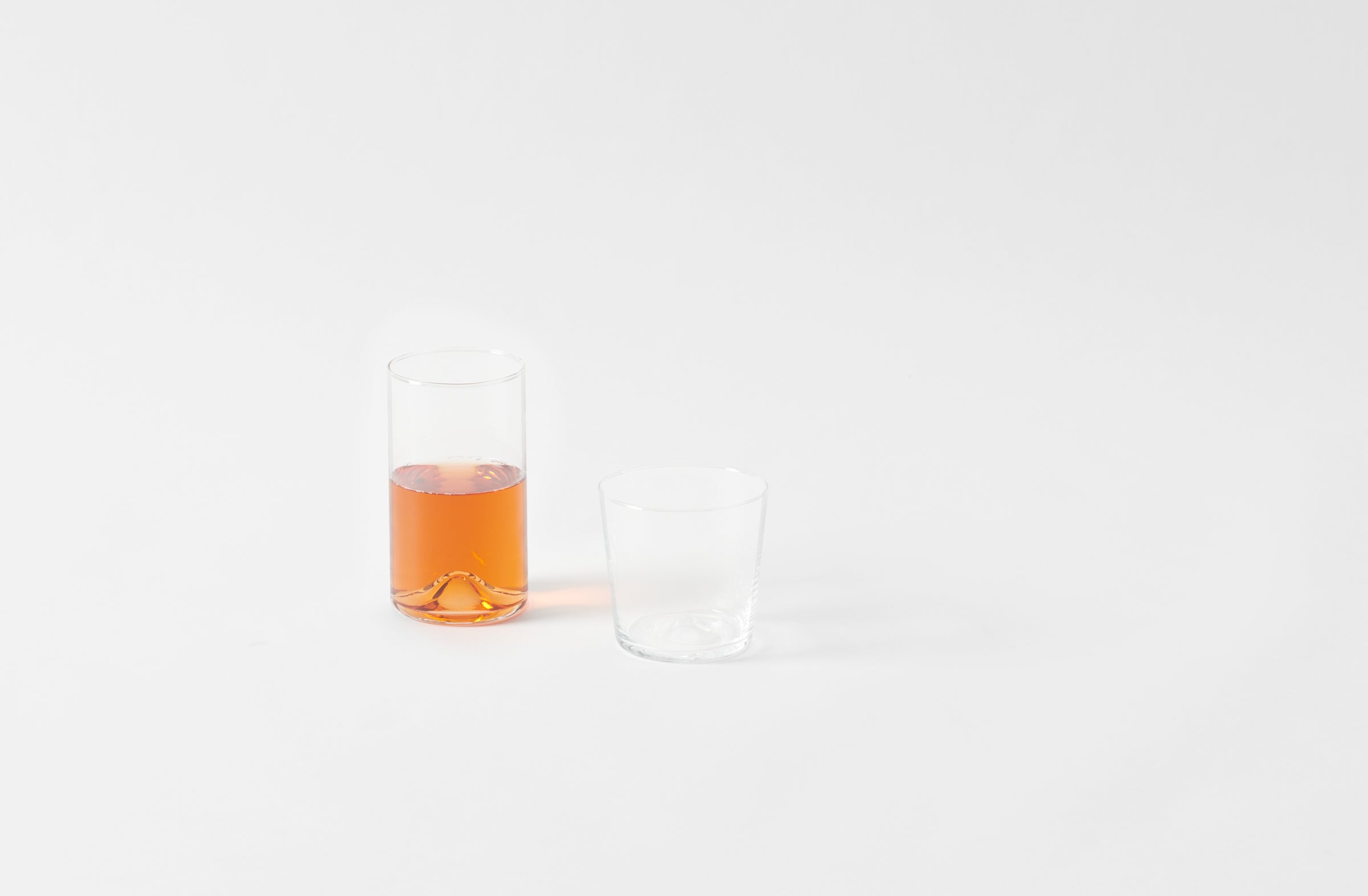 Clear glass with orange liquid on a white background. Default
