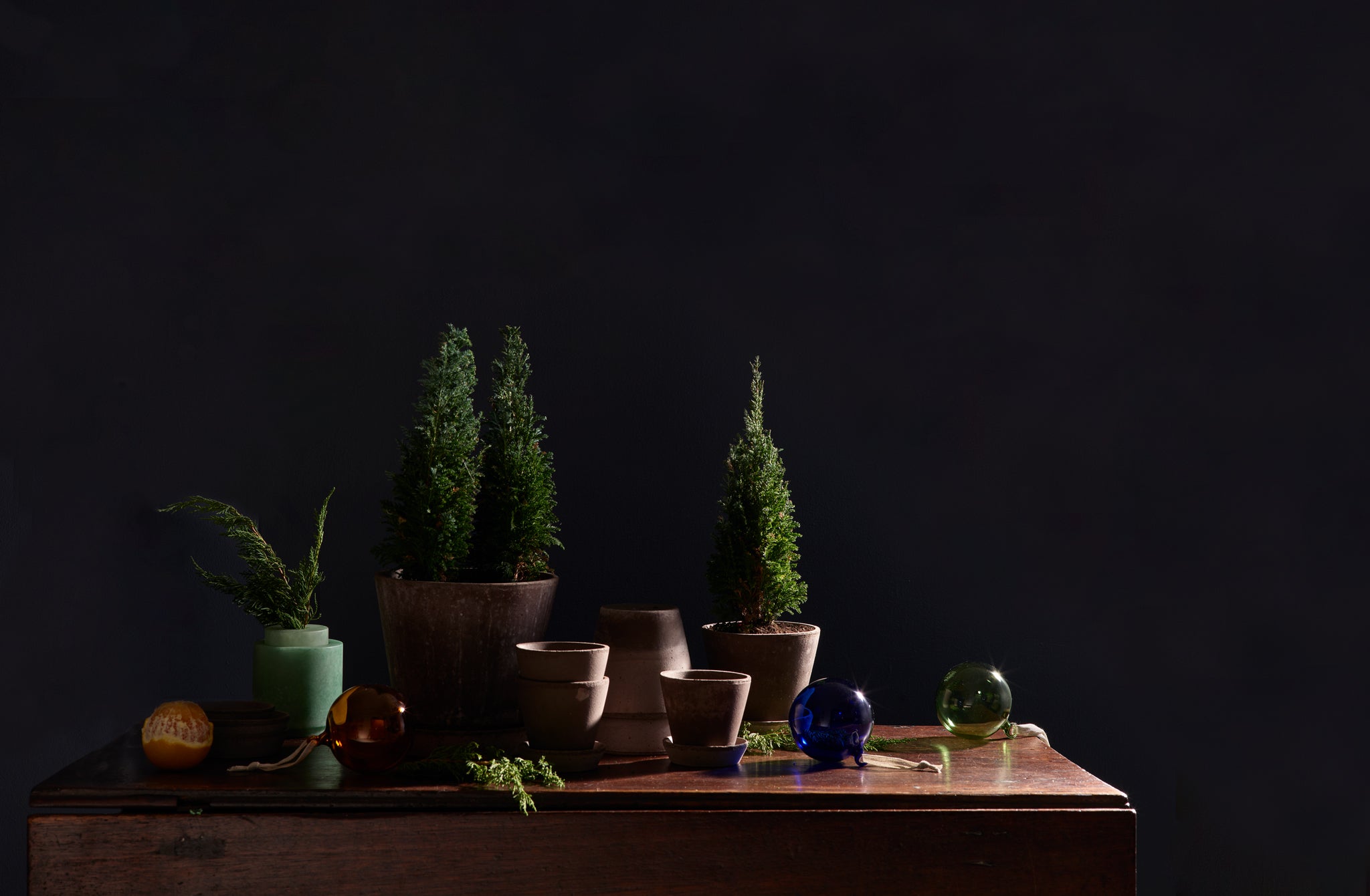 Small potted trees in Berg grey pots on antique table with glass ornaments
