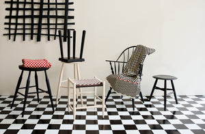 A mix of modern traditional seating in black and white from Sawyer Made Oja Design Blackcreek Mercantile and Sawkille with a Jonathan Kline sculpture on a checkered floor with red accents.