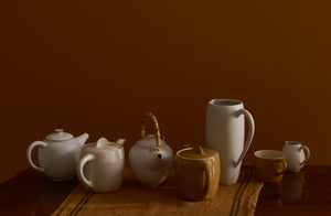 Christiane Perrochon and Brickett Davda pots and pitchers in cream and ochre on top of a Charvet cider colored linen kitchen towel with stripes.