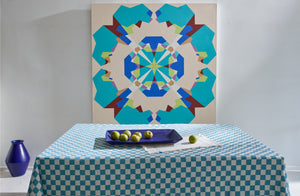 Christiane Perrochon blue violet large rectangular tray holding green apples and sitting on a turquoise check tablecloth below vibrant geometric Leslie Wilkes painting.