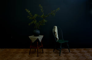 Christiane Perrochon bottle green glazed large boule holding branches of oak next to a hunter green Sawyer Made Windsor side chair.