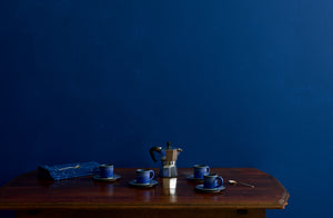Christiane Perrochon bright blue espresso service for four on antique table against a blue wall.