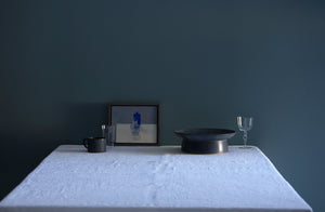  Christiane Perrochon grey blue cake stand and mug with Lobmeyr Poppea glass next to small Jason Line painting on table against blue grey wall.