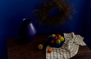 Christiane Perrochon blue violet vase and cakestand holding apples with cooks cloth kitchen towel.