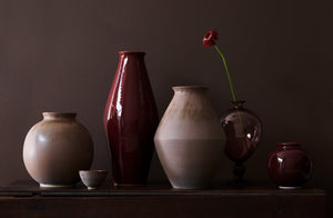 Christiane Perrochon stoneware vases in browns and bordeauxs set in a tableau with a murano amethyst vase set with a single flower