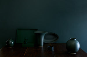 An arrangement of shape and texture in green glassware ceramic vessels and leather storage featuring Christiane Perrochon Michaël Verheyden and Davide Fuin. 