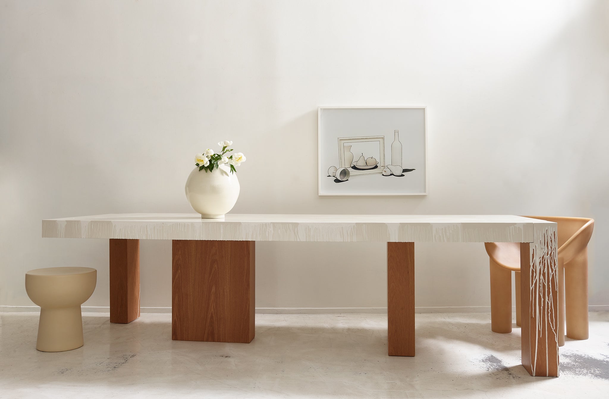 Faye Toogood sculpture table set with a single raw roly poly dining chair, Cynthia Greig still life photograph on the wall behind.