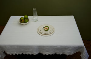 A table simply outfitted with a R&D Labs clear glass Luisa carafe and a single place-setting of Frances Palmer dinnerware holding greengage plums on an off white Sicily tablecloth. Default