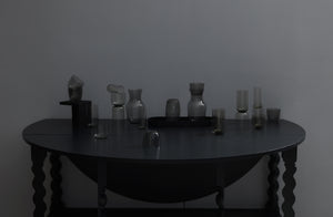 grey glassware still life set with black oval leather tray on dark grey drop leaf table