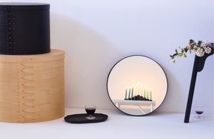 Ifuji black three leg stool tray and bins stacked next to mirror in soft focus reflecting light from MARCH menorah.