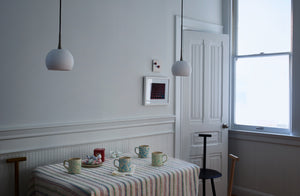 Bright morning table with riga linen tablecloth with celadon on cream and turquoise on cream MARCH splatterware mugs surrounded by Faye Toogood spade chairs in tumeric navy and ash.