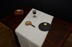 Lobmeyr Hoffman wine glass stands at the center of a table on top of runner next to a loaf of bread and a large Takashi Endo plate holding a pat of butter at the ready for a Forge de Laguiole Andrée Putman Ebony Butter Knife to butter a slice of bread.