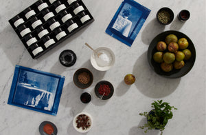 Tabletop scene with various items including a box of tea, bowls with snacks, and apples on a light gray surface. Default 