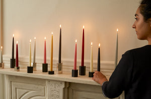 Mixed-silver-and-steel-menorah-with-different-colored-taper-candles-on-mantle