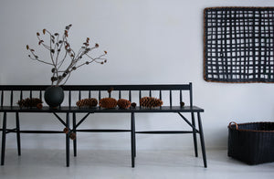 Sawkille Co. Rabbit Bench with a grouping of pinecones and branches in a Karen Swami black on red stoneware round vessel next to Jonathan Kline basket and large black tray sculpture.