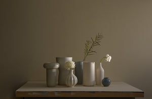Assortment of vases in cream and grey on tabletop.