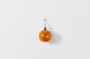 Single amber glass ornament strung with linen tape